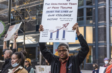 Rodney Babb holds a sign saying that Penn Trauma's healthcare workers take care of victims of gun violence but wish they didn't have to, at a rally protesting gun violence.