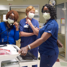 Nurses stand at a computer station in the HUP Cedar intensive care unit.